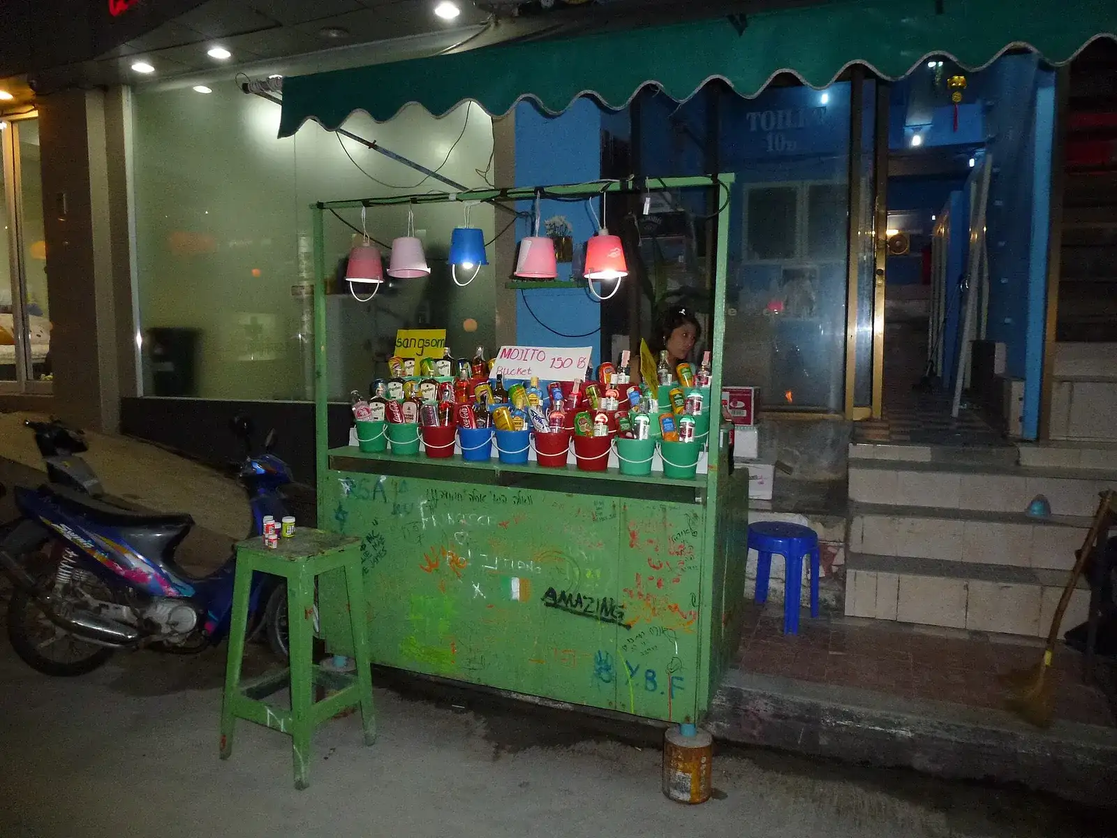 Small street stall selling cocktail buckets at night in Thailand