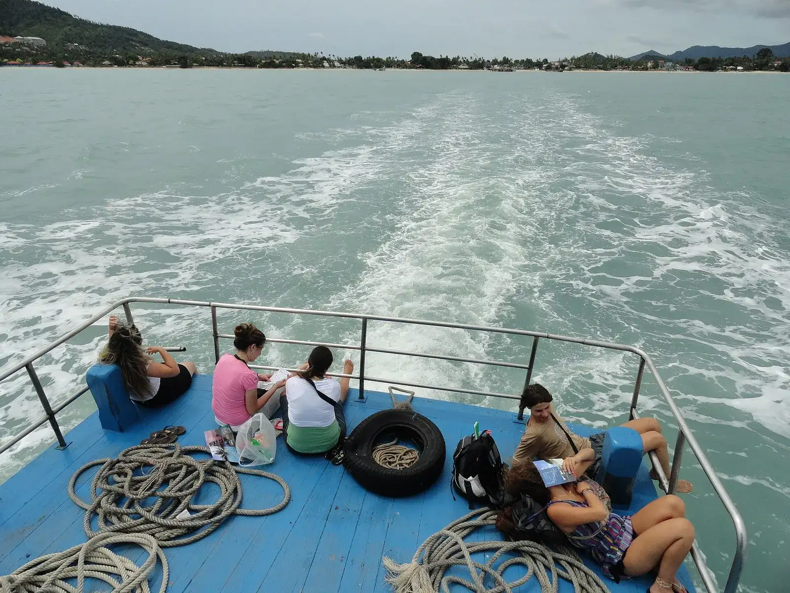 Passengers on a ferry deck watching the wake in the Gulf of Thailand