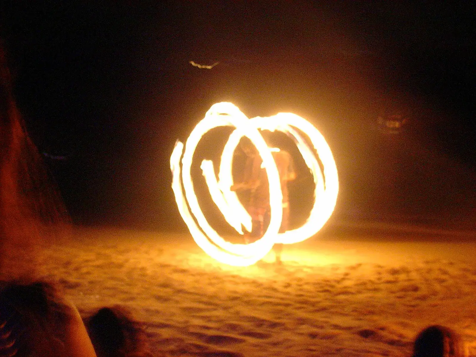 Fire dancer spinning flaming poi on the beach at the Full Moon Party